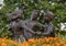 Bronze statue of a boy and two girls happily dancing in a circle in a bed of orange flowers in Irving, Texas.