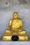 Bronze statue of sitting monk with grey concrete background