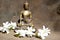 Bronze statue of Touching earth Buddha on wood with white flowers