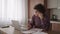 Brooding serious curly freelancer man sit at table in comfortable home office room work on laptop looks concentrated