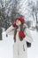 Brooding young woman in red knitted hat and mittens walks through snow-kept park. Winter day