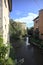 Brook bordered by houses and plants on a sunny day in the italian countryside