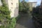 Brook bordered by houses and plants on a sunny day in the italian countryside