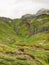 Brook in fresh Alps meadow, snowy peaks of Alps in background. Cold misty and rainy weather in mountains at the end of fall.