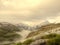 Brook in fresh Alps meadow, snowy peaks of Alps in background. Cold misty and rainy weather in mountains at the end of fall.