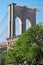 Brooklyn Bridge pillar and green trees in New York