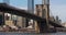 The Brooklyn Bridge stands against a blue sky downtown Manhattan skyscrapers.