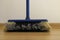 A broom with dust is standing on a parquet floor in a flat