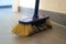 A broom with dust is standing on a tiled floor in a  flat