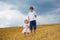 Brother and baby sister walking in a golden wheat field