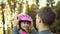 Brother helps the girl to put on a safe helmet before riding a bike on a Sunny autumn day in nature and give five to each other .