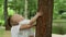 Brother holding boy on hands in park. Boy helping toddler to climb tree