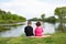 Brother and little sister sitting on the bank of the river.