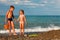 Brother and sister hold hands and stand on beach