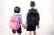 Brother and sister holding backpack on white background