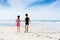 Brother sister holding hand walk on the beach to colleact bottle