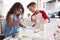 Brother and sister preparing cake mixture together at the kitchen table, waist up