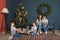 Brother and sister pull a new year present box in the living room with a Christmas tree, and parents in the family look laughing