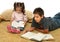 Brother and sister reading books on the floor