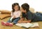 Brother and sister reading books on the floor