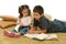 Brother and sister reading books on the floor