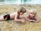 Brother and sister relaxing on sand near lake