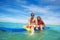 Brother and sister sit swim on surf board in sea