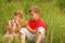 Brother and sister sitting in tall grass and play