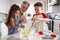 Brother and sister standing at the kitchen table making cake mix with their grandfather, close up