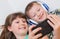 Brother and sister are taking a selfie lying on the couch at home