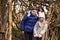 Brother and sister under shelter of branches look to camera