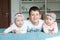 Brother and sisters lie on the bed and smiling. Brother embraced his little twin sisters. They are very happy with each other