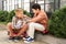 Brothers talking while sitting on pavement near green bushes