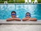 brothers wearing swimsuits and glasses Smile while perched on the edge of the pool