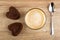 Brow biscuits in form of heart, cappuccino in cup, spoon on table. Top view