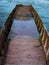 Brown abandoned row boat, vintage wodden boat sinking floating on the water.