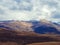 Brown autumn Caucasian mountains covered with snow on the peaks under the clouds. A sharp temperature drop in the