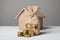 Brown bag with logo of dollar, euro and yuan. Gold coins and homemade paper house. Concept renting and buying home, property taxes