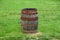 A brown barrel with rusty metal on the top of green grass