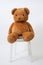 brown bear doll siting on wood chair