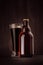 Brown beer bottle belgian steinie and glass pilsner with porter on dark wood board, vertical, mock up.