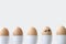Brown boiled eggs in a row, one with hand drawn smiley face, copy space