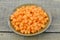 Brown bowl with diced carrots on wooden table, closeup