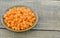 Brown bowl with diced carrots on wooden table, closeup