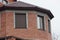 Brown brick attic of a private house with windows closed with roller shutters