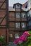 Brown brick building with white windows, pink flowers in the front. Typical architecture of Hamburg.