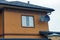 Brown brick house with a window and black satellite dishes