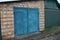 Brown brick wall garage facade with metal blue gates