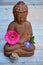 Brown Buddha statue with flowers and zen stones