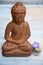 Brown Buddha statue with flowers and zen stones